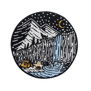 May include: Embroidered patch featuring a night scene with a mountain range, a waterfall, a tent, a campfire, and a crescent moon. The sky is black with white stars. The patch is circular and has a black border.