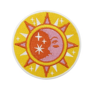 Może przedstawiać: Żółta naszywka z haftem przedstawiającym słońce i księżyc. Słońce jest pomarańczowe i ma białe gwiazdy w środku. Księżyc jest różowy i ma twarz.