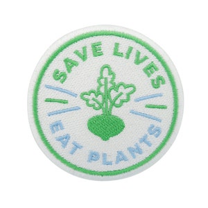 Può includere: Toppa ricamata verde e bianca con il testo "Save Lives Eat Plants" e un'illustrazione di rapa verde.