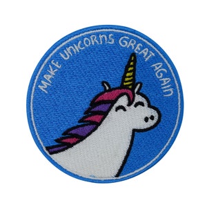 Könnte beinhalten: Ein blauer gestickter Aufnäher mit einem weißen Einhorn mit einer rosa und violetten Mähne und einem gelben Horn. Der Text "MAKE UNICORNS GREAT AGAIN" ist um das Einhorn herum gestickt.