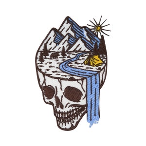 Könnte beinhalten: Gestickter Aufnäher mit einem braunen Schädel, in dessen Kopf sich eine Berglandschaft befindet. Die Landschaft umfasst einen Fluss, ein Zelt und eine Sonne. Der Fluss fließt als Wasserfall aus dem Schädel.