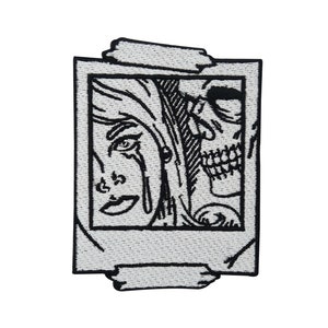 Puede incluir: Parche bordado en blanco y negro de la cara de una mujer y una calavera dentro de un marco de imagen. El marco tiene un borde desgarrado y está delineado en negro.