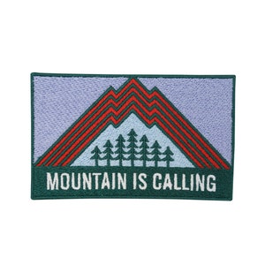 Può includere: Toppa ricamata verde con un design a catena montuosa in rosso e bianco. Il testo "MOUNTAIN IS CALLING" è ricamato in bianco nella parte inferiore della toppa.