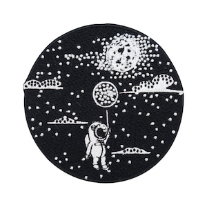 Könnte beinhalten: Ein gestickter Patch in Schwarzweiß, der einen Astronauten zeigt, der einen Ballon im Weltraum hält. Der Astronaut trägt einen Raumanzug und einen Helm. Der Ballon ist rund und hat ein Sternenmuster. Der Hintergrund ist ein schwarzer Kreis mit weißen Sternen und Wolken.