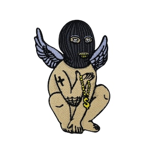 Op de afbeelding: Een geborduurde patch in zwart en wit van een cherub die een zwarte ski-masker draagt en een gouden ketting met een dollar-teken bedel vasthoudt. De cherub heeft vleugels en een kruis tatoeage op zijn arm.