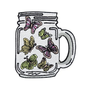 May include: A white mason jar with a black lid and handle, filled with colourful butterflies. The butterflies are pink, yellow, and green.