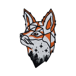 May include: An embroidered patch of a fox's head with a geometric design in orange and white. The fox's head is outlined in black and has a forest scene at the bottom.