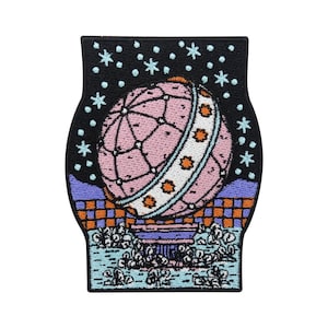 Könnte beinhalten: Ein gestickter Patch mit einem Globus-Design in Rosa und Weiß auf schwarzem Hintergrund. Der Globus ist von Sternen und einem karierten Muster umgeben. Der Patch ist perfekt, um Kleidung, Taschen oder anderen Accessoires eine einzigartige Note zu verleihen.