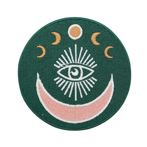 May include: A green embroidered patch with a white crescent moon, a white eye with a white sunburst, and three gold crescent moons.