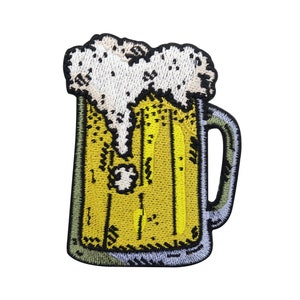 Könnte beinhalten: Ein gestickter Aufnäher, der eine Bierkrüge mit weißem Schaum oben zeigt. Der Krug ist gelb mit schwarzem Umriss und weißem Henkel.