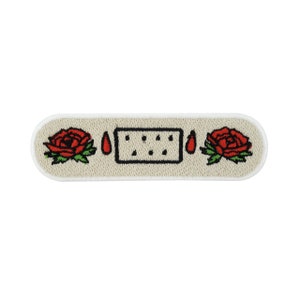 Può includere: Toppa ricamata bianca con un cerotto, due rose rosse e due gocce di sangue rosse.