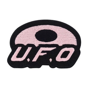 Könnte beinhalten: Schwarzer und rosa gestickter Aufnäher mit dem Text "U.F.O." in rosa. Der Aufnäher zeigt eine stilisierte UFO-Form.