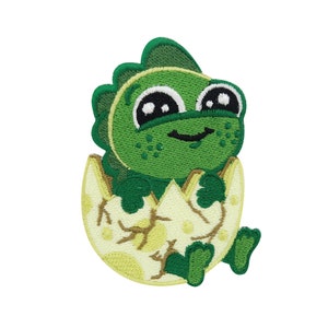 Könnte beinhalten: Gestickter Aufnäher mit einem Cartoon-Baby-Dinosaurier, der aus einem Ei schlüpft. Der Dinosaurier ist grün mit großen schwarzen Augen und einem freundlichen Lächeln. Die Eierschale ist cremefarben mit braunen Akzenten. Der Aufnäher ist für Kleidung oder Accessoires bestimmt.