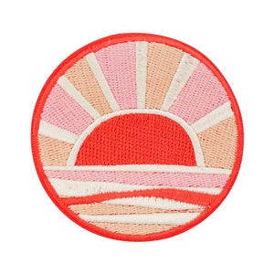 Könnte beinhalten: Ein runder gestickter Patch mit einem roten, rosa und weißen Sonnenuntergangsdesign. Die Sonne ist ein großer roter Halbkreis mit weißen Strahlen. Der Horizont ist eine Reihe von rosa und weißen Streifen.