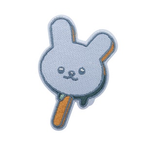 Peut inclure: Un patch brodé bleu en forme de sucette de lapin avec un bâton brun.