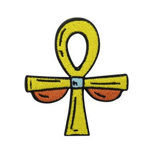 Könnte beinhalten: Ein gesticktes Ankh-Symbol in Gelb mit orangefarbenen und blauen Akzenten. Das Ankh ist ein altes ägyptisches Hieroglyphensymbol, das das Leben darstellt.