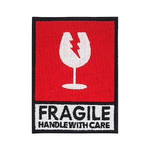 Pode incluir: Patch bordado vermelho e branco com um símbolo de copo quebrado e o texto "FRAGILE HANDLE WITH CARE".