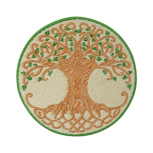 Puede incluir: Un parche bordado circular que presenta un diseño estilizado del árbol de la vida. El árbol está contorneado en verde y relleno con un color marrón claro. El fondo es de color crema.