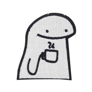 Op de afbeelding: Witte geborduurde patch met een cartoonfiguur die een dampende kop koffie vasthoudt. Het personage heeft een eenvoudig, afgerond ontwerp met een glimlach.