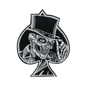 Könnte beinhalten: Schwarz-weiß gestickter Patch eines Schädels mit Zylinder und Sakko, in Form einer Pik-Spielkarte.