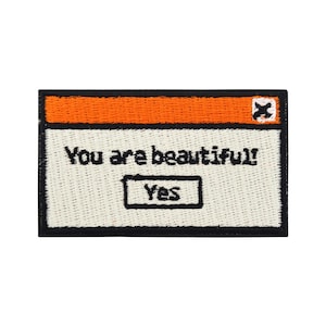 May include: Embroidered iron-on patch with a white background and black outline. The patch features a blue and orange computer window with the text "You are beautiful!" and a black button that says "Yes".