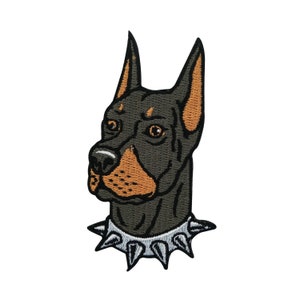 May include: Black and brown embroidered patch of a Doberman Pinscher dog head with a silver studded collar.