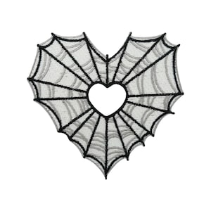 Op de afbeelding: Zwarte en witte geborduurde patch in de vorm van een hart met een spinnenwebontwerp. Het midden van het hart is uitgesneden.
