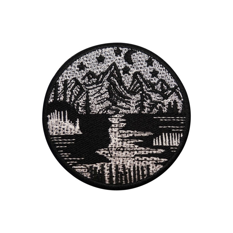 Könnte beinhalten: Schwarz-weiß gestickter Aufnäher mit einer Bergszene und Sternen. Die Berge sind im Hintergrund und im Vordergrund befindet sich ein See mit einer Spiegelung der Berge.
