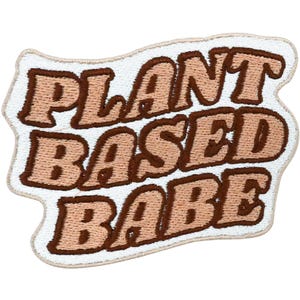 Pode incluir: Patch bordado com as palavras "PLANT BASED BABE" em letras castanhas e bege. O patch tem uma borda branca ondulada. Este patch foi projetado para ser passado a ferro ou costurado em roupas ou acessórios.