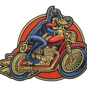 Pode incluir: Etiqueta bordada com um lobo de desenho animado a andar de moto com chamas a sair do pneu traseiro. O lobo está a usar calças de ganga azuis e uma jaqueta preta. A moto é vermelha com um motor e rodas douradas. A etiqueta tem um círculo vermelho e laranja à volta com o número "13" no lado da moto.