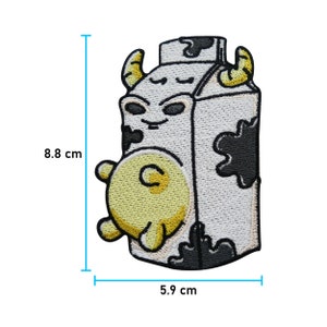 May include: A white and black cartoon milk carton with a cow's face and a yellow udder. The carton is 5.9 cm wide and 8.8 cm tall.
