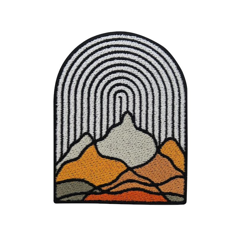 May include: An embroidered patch depicting a stylised mountain range with a rainbow arch above. The mountains are in shades of orange, brown, and green, while the rainbow is white and black.