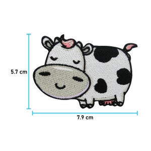 May include: Embroidered patch of a cartoon cow with a smiling face. The cow is white with black spots and pink accents. The patch measures 7.9 cm wide and 5.7 cm high.