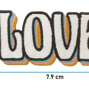 Puede incluir: Un parche bordado blanco con la palabra "LOVE" en estilo retro. Las letras est&aacute;n delineadas en marr&oacute;n, con un borde amarillo, rosa y azul. El parche mide 3,9 cm de alto y 7,9 cm de ancho.