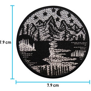 Puede incluir: Parche bordado en blanco y negro que representa una cordillera con un lago en primer plano. El parche es circular y mide 7,9 cm de di&aacute;metro.