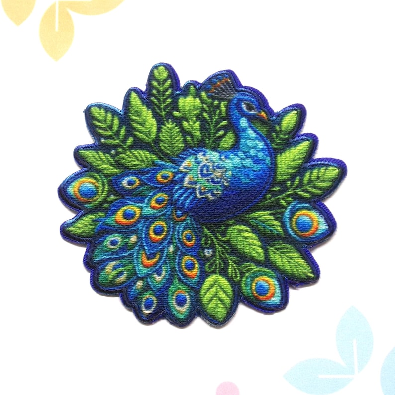 Pu&ograve; includere: Una toppa colorata a forma di pavone con un design dettagliato. Il pavone &egrave; principalmente blu con accenti verdi, gialli e arancioni. La toppa &egrave; circondata da foglie verdi e ha un bordo blu scuro. Adatta per abbigliamento o accessori.