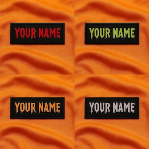 May include: Four black rectangular patches with the text "YOUR NAME" in different colors: red, green, yellow, and white. The text has a dripping effect. The patches are on an orange fabric background.