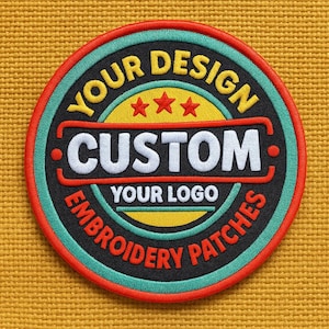May include: Circular embroidered patch with the text "YOUR DESIGN" and "EMBROIDERY PATCHES" in yellow and black. The word "CUSTOM" is in white. The patch has a red, teal, and black color scheme, with a yellow background.