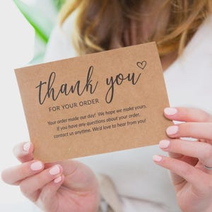 Puede incluir: Una tarjeta de agradecimiento rectangular de papel kraft marr&oacute;n con texto impreso en negro que dice thank you FOR YOUR ORDER seguido de un mensaje sobre la satisfacci&oacute;n del pedido y datos de contacto con un peque&ntilde;o icono de coraz&oacute;n.