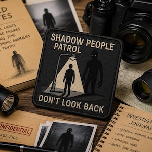 May include: A square black embroidered patch featuring the text SHADOW PEOPLE PATROL and DON'T LOOK BACK in tan lettering. The design depicts a silhouette standing under a streetlamp with a second shadow figure nearby, all in tan and black thread.
