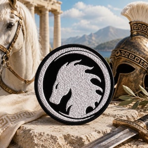 May include: A circular black and white embroidered patch with a horse head design. The patch is set against a backdrop including a white horse, a bronze helmet, and a sword, evoking a historical or mythological aesthetic.