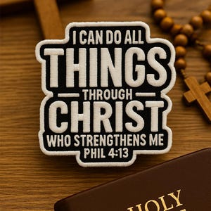 Può includere: Una toppa con la scritta "I CAN DO ALL THINGS THROUGH CHRIST WHO STRENGTHENS ME PHIL 4:13" in bianco su sfondo nero. Una Sacra Bibbia rilegata in pelle marrone, una croce di legno e un rosario sono anch'essi visibili.