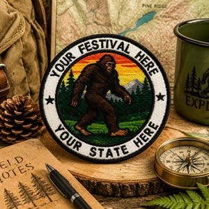 May include: Embroidered patch with a Bigfoot design, encircled by the words "Your Festival Here" and "Your State Here." The image includes a compass, a green enamel mug, and other outdoor-themed items, creating a rustic aesthetic.