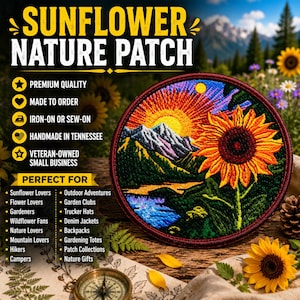 Op de afbeelding: Een ronde geborduurde patch met een levendig landschap met een grote gele zonnebloem op de voorgrond, besneeuwde bergen, een felle zon en een blauwe rivier. De patch heeft een donkerrode rand en wordt getoond met een kompas.