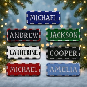 May include: Rectangular embroidered patches in various colors, each displaying a name in white thread. Names include MICHAEL, ANDREW, JACKSON, CATHERINE, COOPER, and AMELIA. The patches have a stitched border in contrasting colors, such as red, black, and green.