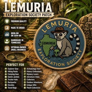May include: A circular embroidered patch featuring a lemur wearing a brown hat, holding a small green alien skull and a hammer. The patch displays a green map outline, blue water, and the text LEMURIA EXPLORATION SOCIETY in gold lettering.