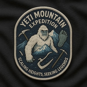 Może przedstawiać: Haftowana naszywka z motywem Yeti. Naszywka przedstawia białego Yeti na tle niebieskich gór, z napisem "Yeti Mountain Expedition" i "Scaling Heights, Seeking Legends". Zawiera czekany i odcisk stopy.