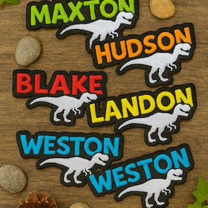 May include: Embroidered name patches with a dinosaur design. Each patch features a name in a different color, including Maxon, Hudson, Blake, Landon, and Weston. The dinosaur is white, and the patches have a black border.