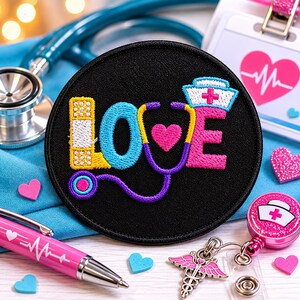 Può includere: Una toppa rotonda nera con la parola "LOVE" ricamata con filo colorato. La "L" è una benda, la "O" è uno stetoscopio e la "E" è un cappello da infermiera. Sono visibili anche una penna rosa con un disegno a battito cardiaco e un badge da infermiera.
