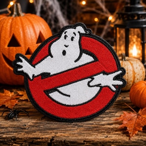 May include: A circular embroidered patch featuring a white cartoon ghost character centred within a red circle with a thick black border. A diagonal red bar crosses the centre of the circle, partially obscuring the ghost's midsection.